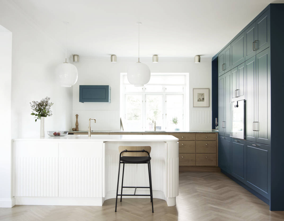 hvidt køkken med eg, marmor og højskabe i blå